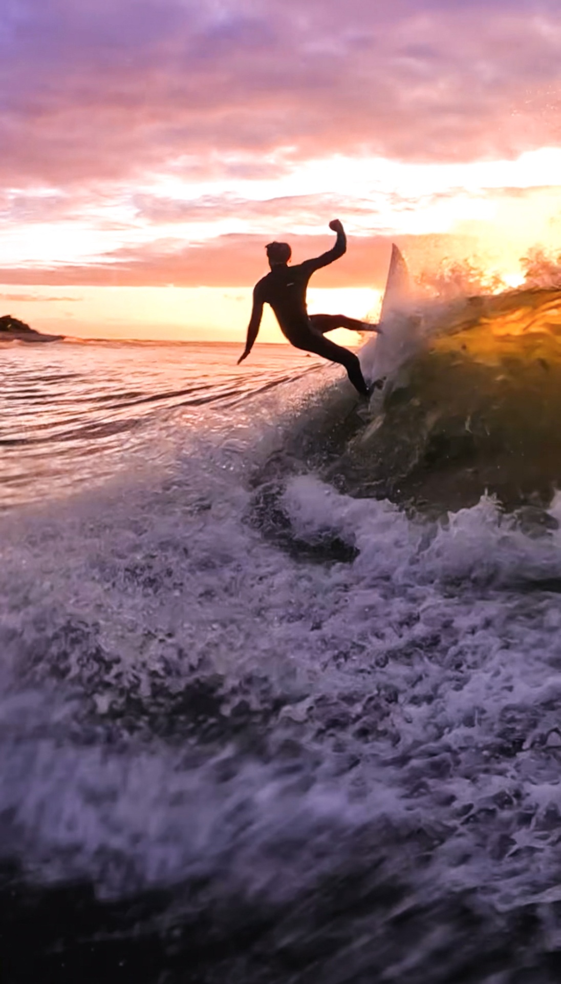 Surfer carving a turn at sunset