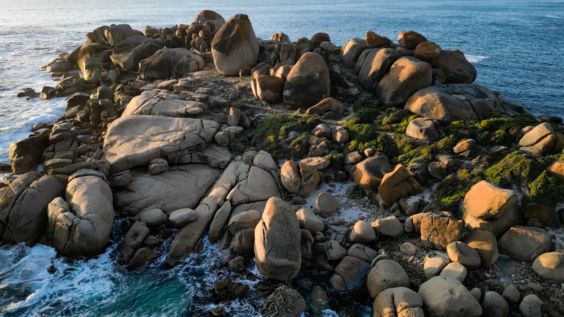 Warm boulders lining a blue coastline