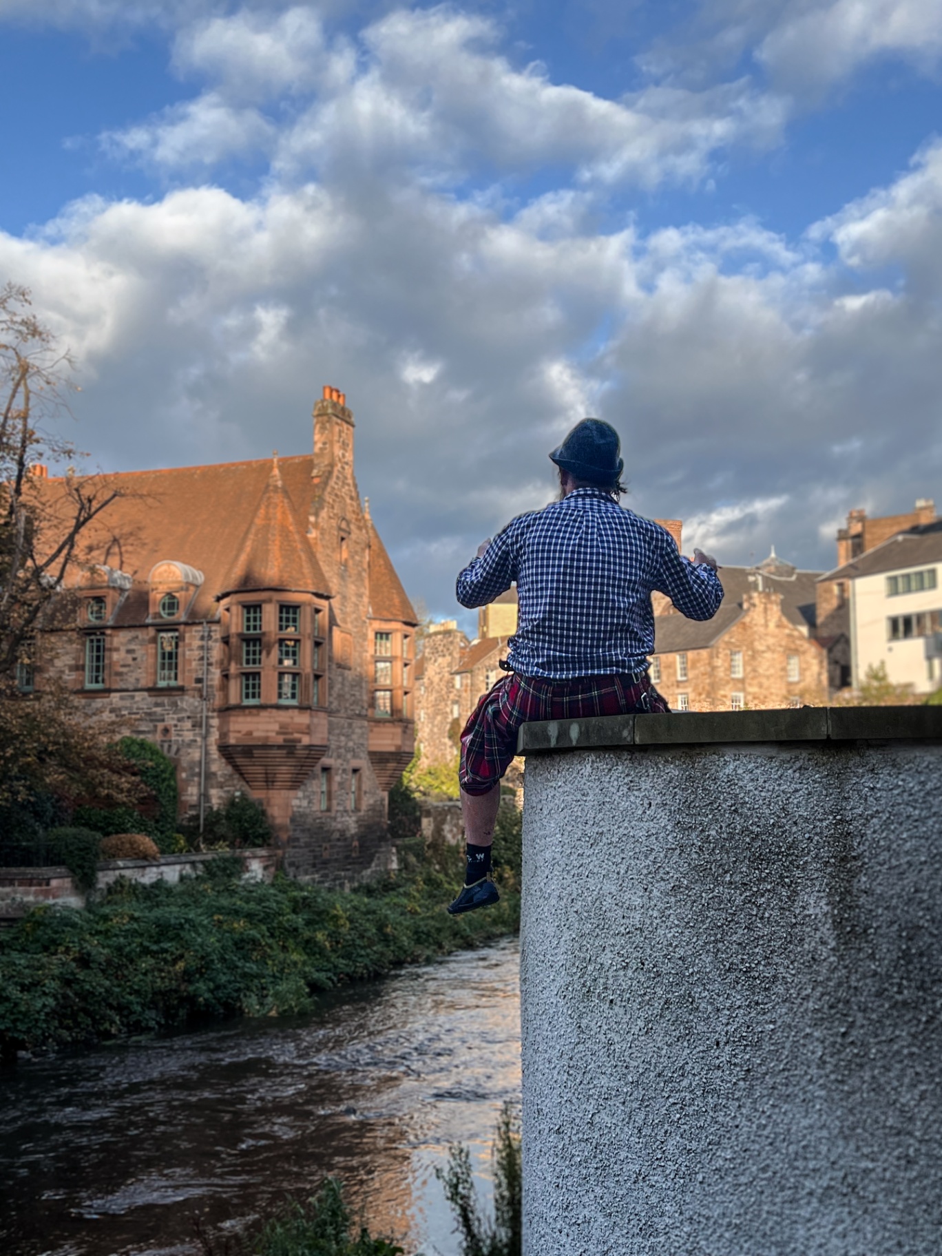 Man in a kilt overlooking a Scottish river town