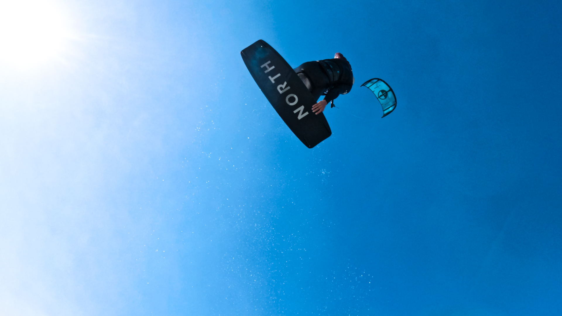 Kitesurfer boosting against a blue sky
